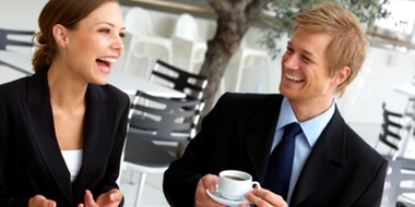 Two young business people enjoy coffee in an outdoor café.